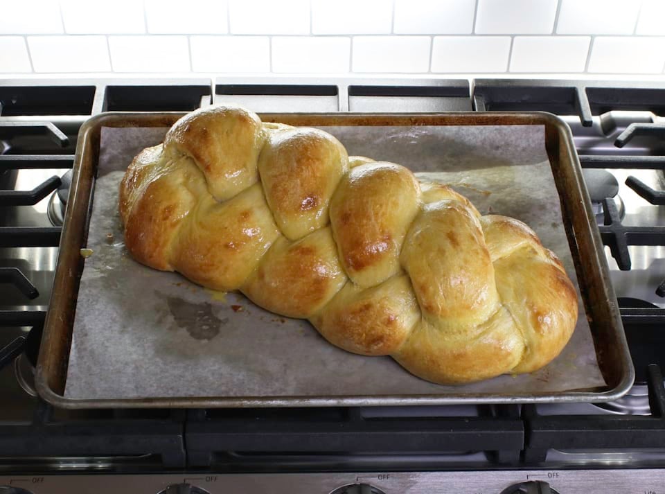 A golden-brown braided challah bread placed on a baking sheet, emphasizing its beautiful shape and crusty exterior.